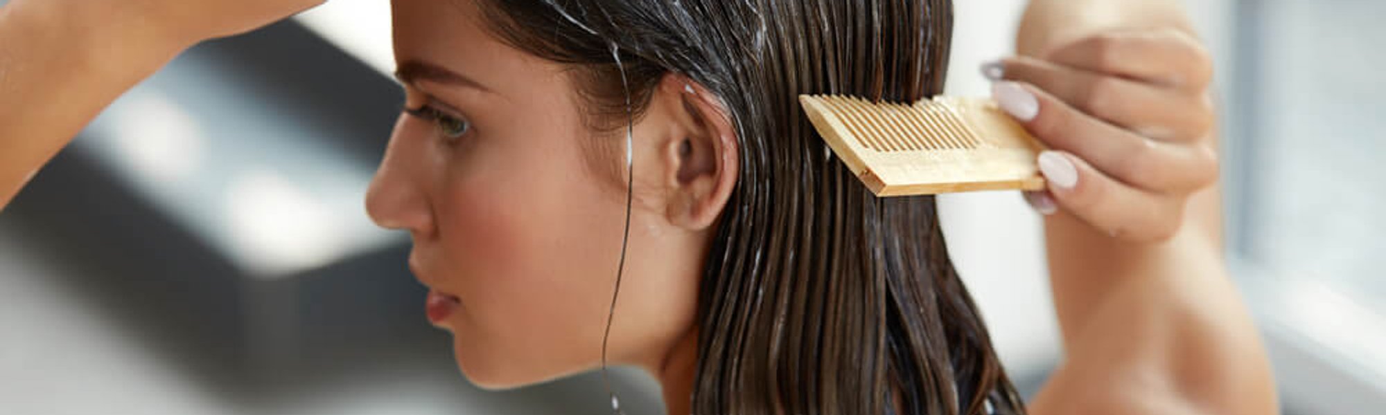 Beautiful woman brushing her wet hair with a wooden comb