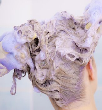 Woman applying coloring shampoo on her hair